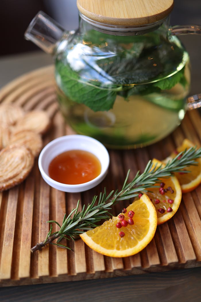 Inviting herbal tea with fresh mint, citrus slices, and rosemary on a wooden tray.