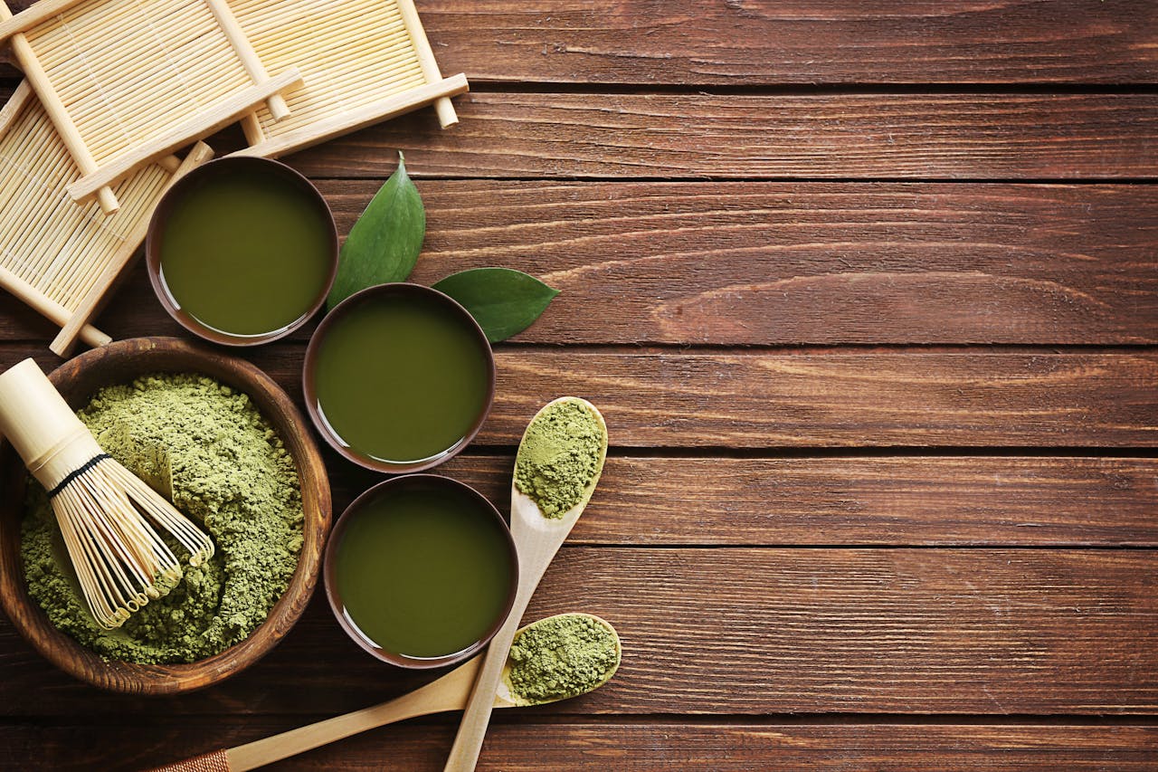 Top view of traditional matcha tea setup with utensils on a wooden table, showcasing a blend of culture and flavor.